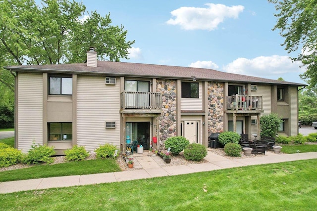 view of property featuring a balcony and a front lawn