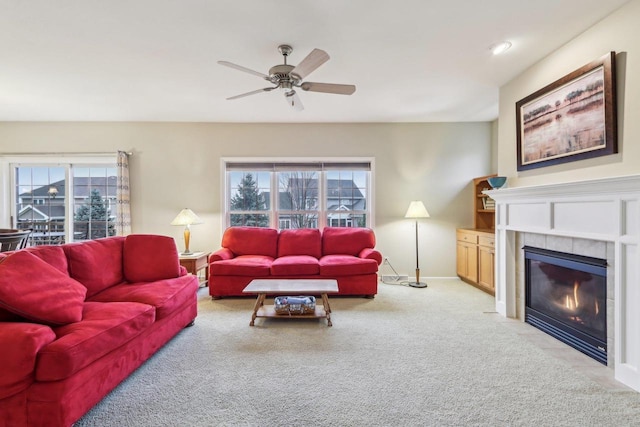 living room featuring ceiling fan, carpet flooring, and a tiled fireplace