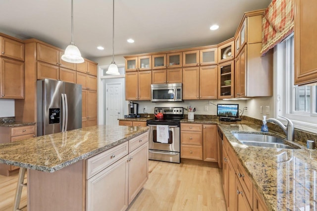 kitchen featuring appliances with stainless steel finishes, light stone countertops, sink, and a kitchen island