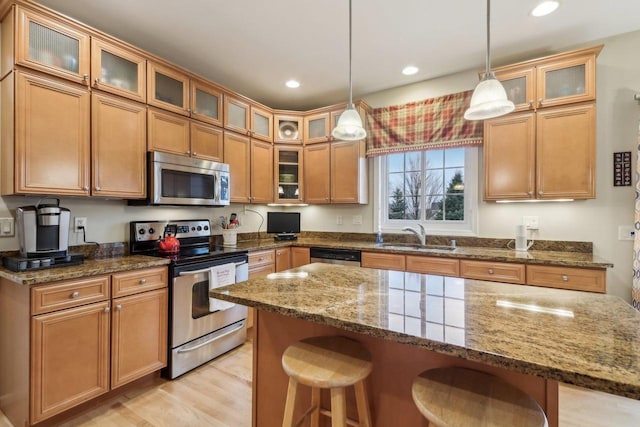 kitchen featuring appliances with stainless steel finishes, pendant lighting, sink, a kitchen bar, and dark stone counters