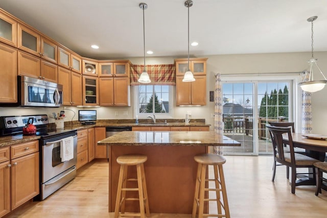 kitchen featuring sink, dark stone countertops, hanging light fixtures, a kitchen breakfast bar, and stainless steel appliances