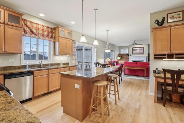 kitchen featuring stone countertops, pendant lighting, sink, a center island, and stainless steel dishwasher