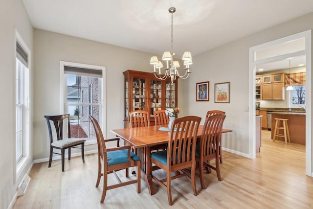 dining area with light hardwood / wood-style floors and a notable chandelier