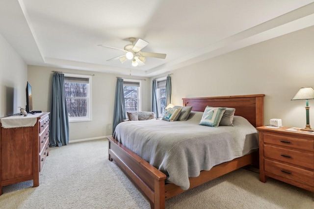 bedroom with a tray ceiling, light colored carpet, and ceiling fan