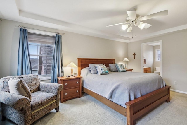 carpeted bedroom featuring a tray ceiling, ceiling fan, and ensuite bathroom