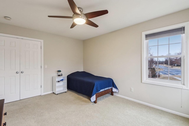 carpeted bedroom featuring ceiling fan and a closet