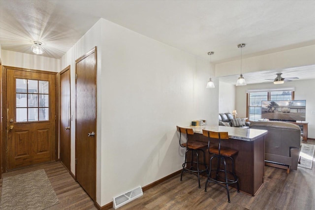 kitchen with pendant lighting, a breakfast bar area, dark hardwood / wood-style flooring, ceiling fan, and kitchen peninsula