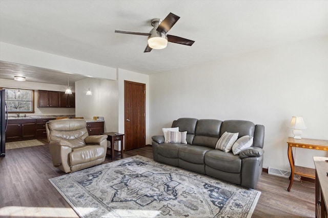 living room featuring dark wood-type flooring, ceiling fan, and sink