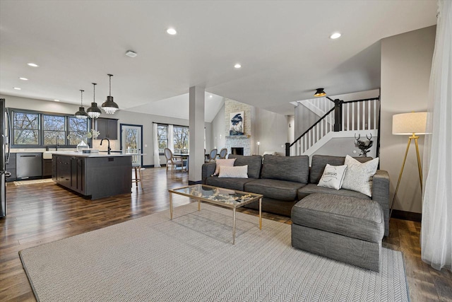 living room featuring dark hardwood / wood-style flooring, sink, a large fireplace, and lofted ceiling