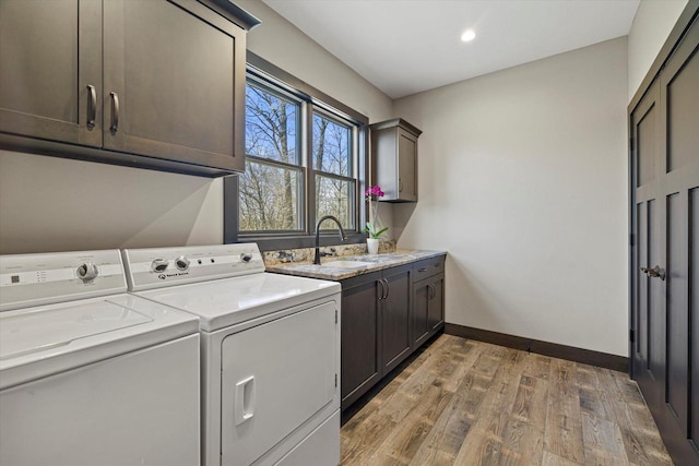 laundry area with wood-type flooring, cabinets, sink, and independent washer and dryer