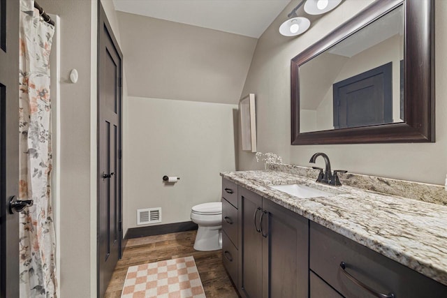 bathroom with toilet, vanity, hardwood / wood-style floors, and vaulted ceiling