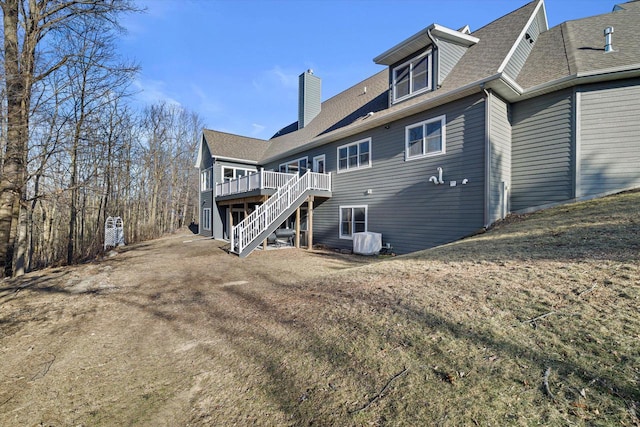 rear view of house with central AC, a deck, and a lawn