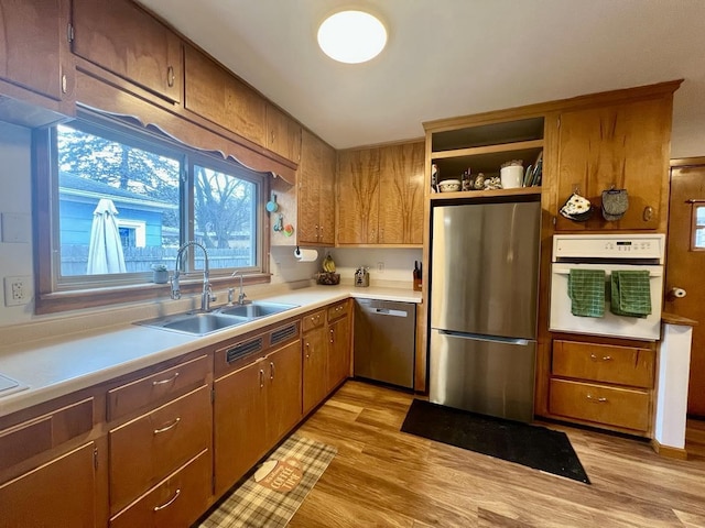 kitchen with stainless steel appliances, sink, and light wood-type flooring