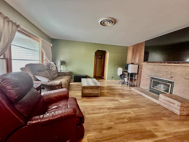 living room with a fireplace and light wood-type flooring