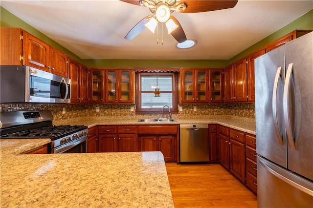 kitchen featuring sink, backsplash, light hardwood / wood-style floors, and appliances with stainless steel finishes