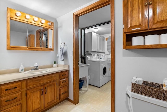 bathroom featuring independent washer and dryer, vanity, toilet, and hardwood / wood-style floors