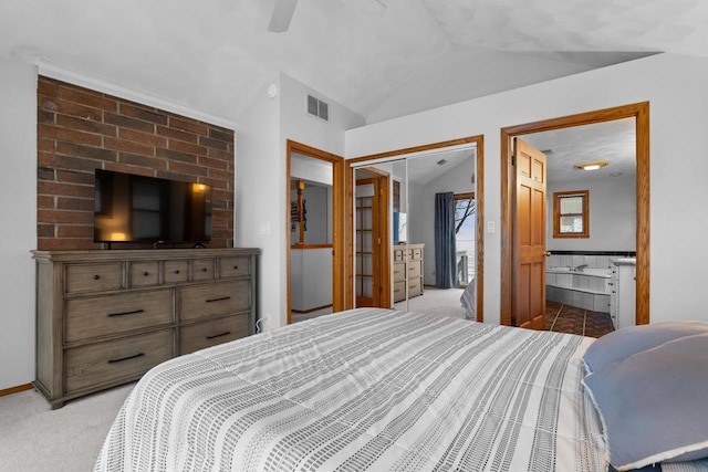 bedroom featuring a closet, ceiling fan, vaulted ceiling, ensuite bathroom, and light colored carpet