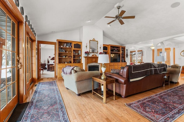 living room featuring lofted ceiling, decorative columns, ceiling fan, and light wood-type flooring