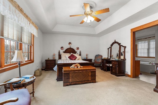 carpeted bedroom with ceiling fan and a tray ceiling