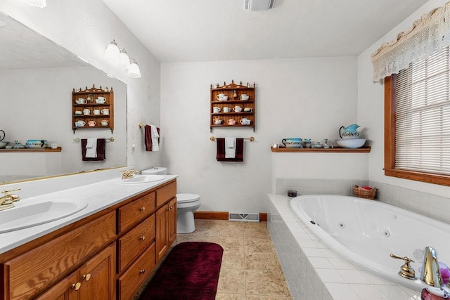 bathroom with toilet, vanity, tiled bath, and tile patterned flooring