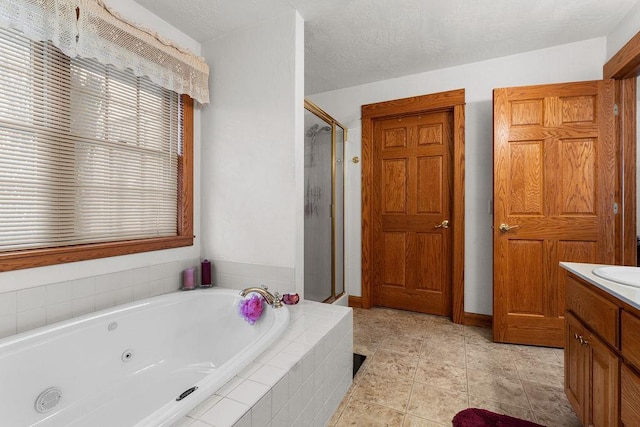 bathroom featuring vanity, a textured ceiling, and separate shower and tub