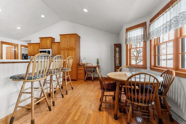 dining room featuring vaulted ceiling, plenty of natural light, light wood-type flooring, and baseboard heating