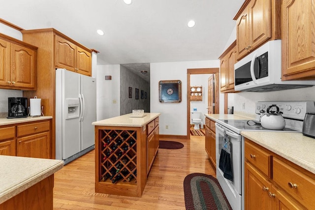 kitchen featuring white appliances, a kitchen island, and light hardwood / wood-style flooring