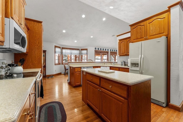 kitchen featuring white appliances, light hardwood / wood-style floors, kitchen peninsula, and a kitchen island