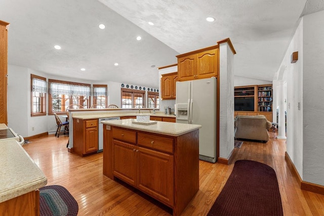 kitchen featuring vaulted ceiling, dishwasher, a center island, white fridge with ice dispenser, and kitchen peninsula