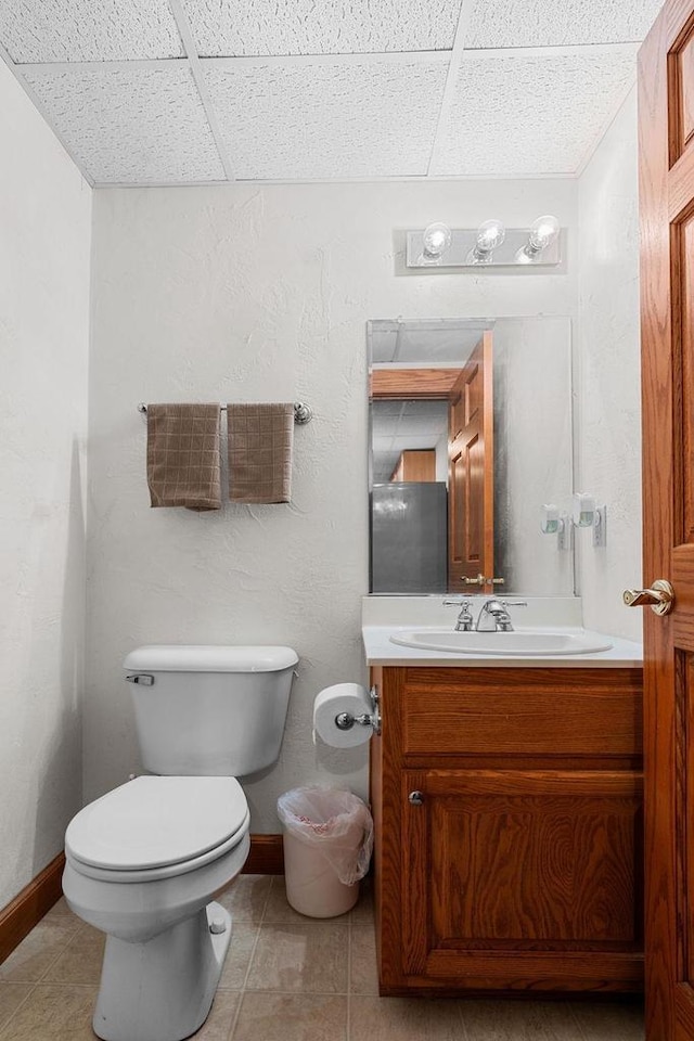 bathroom with vanity, tile patterned flooring, toilet, and a drop ceiling