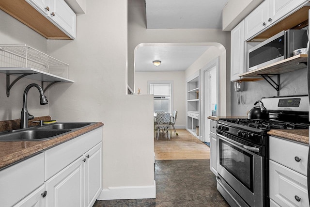 kitchen with white cabinetry, stainless steel appliances, sink, and dark stone counters