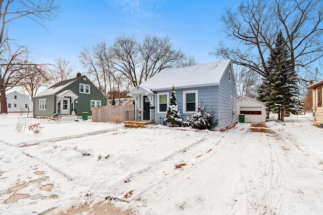 snow covered back of property featuring a garage and an outbuilding