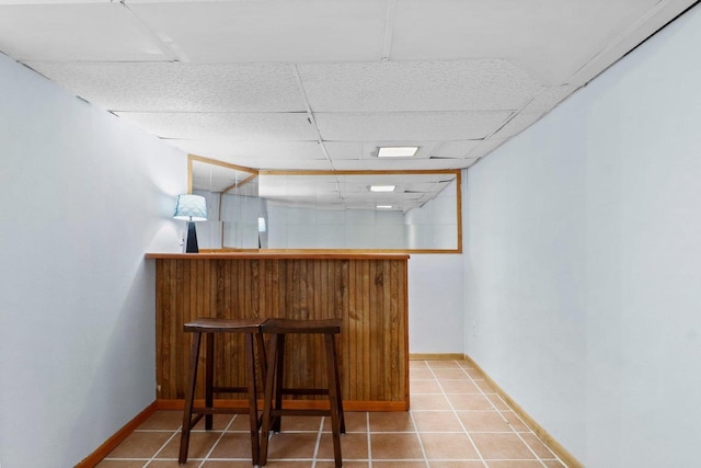 bar featuring tile patterned flooring and a drop ceiling