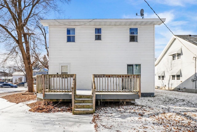 snow covered rear of property with a wooden deck