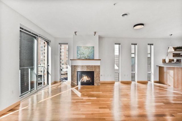 unfurnished living room featuring a tiled fireplace and light hardwood / wood-style floors