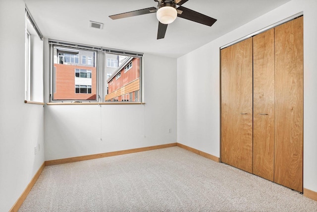 unfurnished bedroom featuring ceiling fan, light colored carpet, and a closet