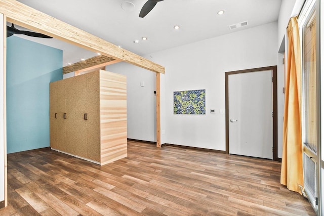 unfurnished room featuring hardwood / wood-style floors, beamed ceiling, and ceiling fan