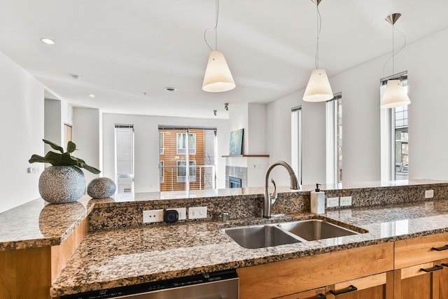 kitchen featuring sink, a wealth of natural light, hanging light fixtures, and stone countertops