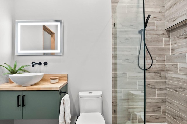 bathroom featuring vanity, a tile shower, and toilet