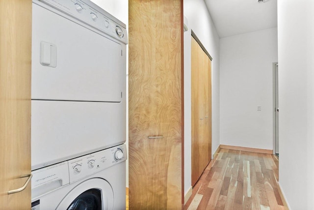 clothes washing area featuring stacked washer and dryer and light hardwood / wood-style floors