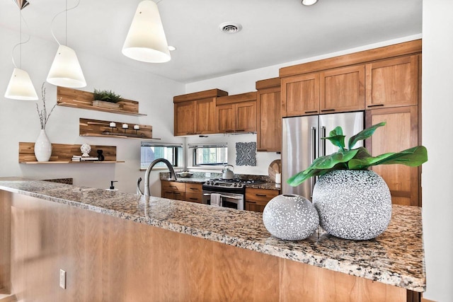 kitchen featuring sink, appliances with stainless steel finishes, light stone counters, decorative light fixtures, and kitchen peninsula