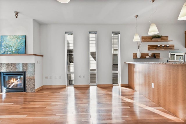 kitchen with pendant lighting, a tile fireplace, and light wood-type flooring