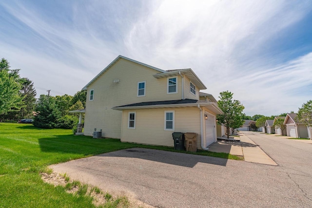 view of property exterior featuring a garage, central AC unit, and a lawn