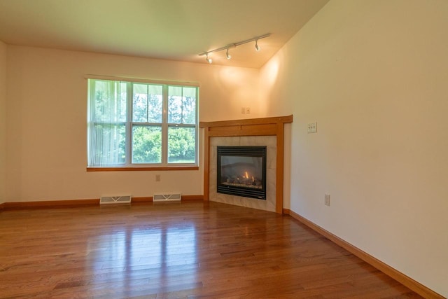 unfurnished living room with hardwood / wood-style flooring, track lighting, and a fireplace