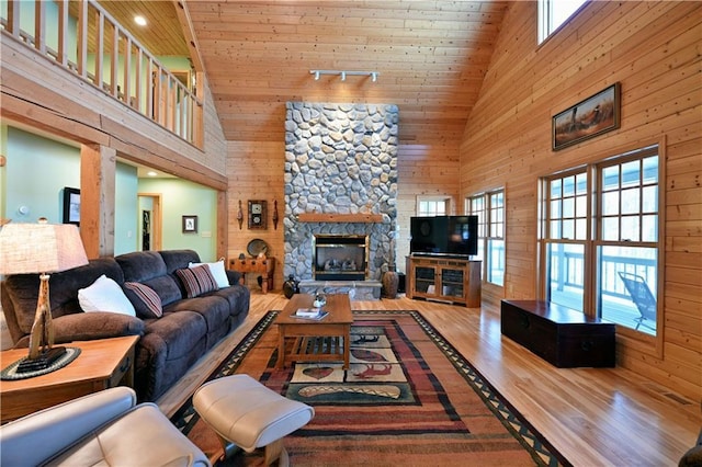 living room with a fireplace, wooden walls, wooden ceiling, and wood-type flooring