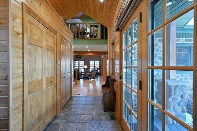 hallway with lofted ceiling, wooden ceiling, and wood walls