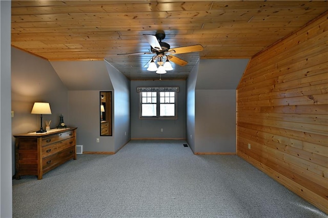 additional living space with lofted ceiling, wood ceiling, ceiling fan, light carpet, and wood walls