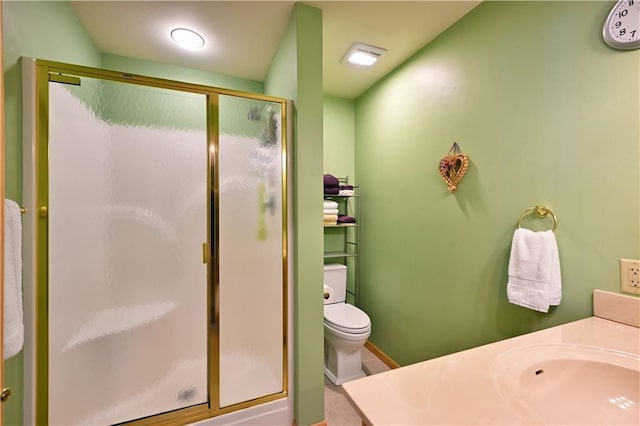 bathroom featuring a shower with door, vanity, tile patterned floors, and toilet