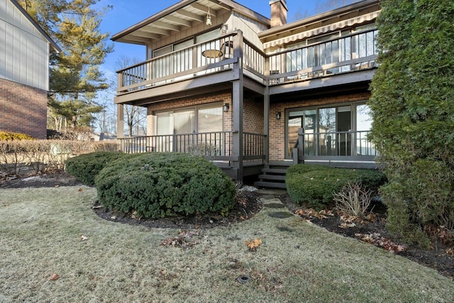 back of house featuring a balcony and a lawn