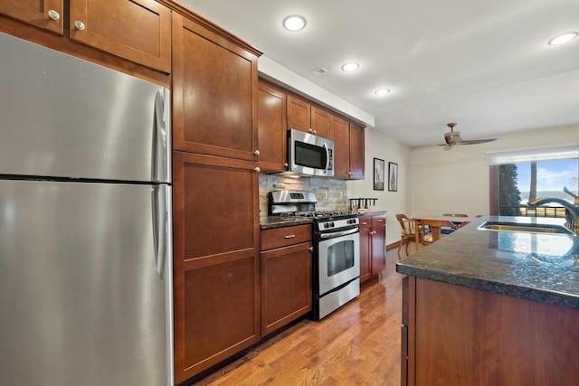 kitchen featuring tasteful backsplash, sink, ceiling fan, stainless steel appliances, and light hardwood / wood-style flooring